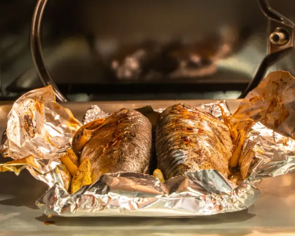 Deux maquereaux entiers, assaisonnés et cuits dans du papier d'aluminium avec des quartiers de citron. Une recette simple et savoureuse.