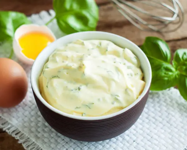 Mayonnaise onctueuse au basilic, avec un œuf et des feuilles de basilic frais.