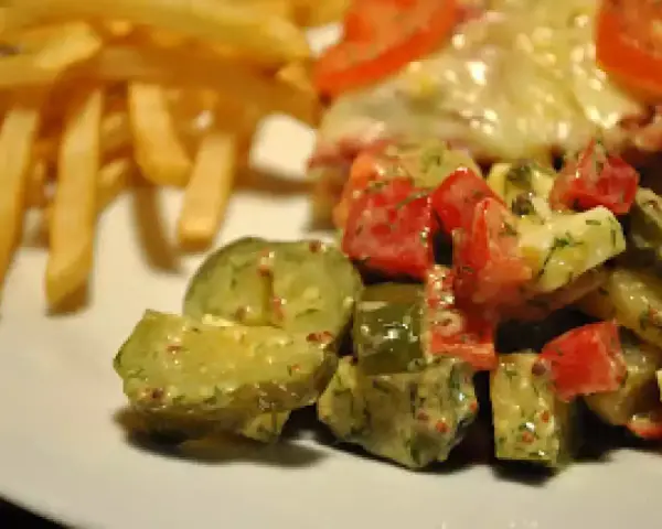 Une délicieuse salade de cornichon avec des tomates et des herbes, accompagnée de frites croustillantes.