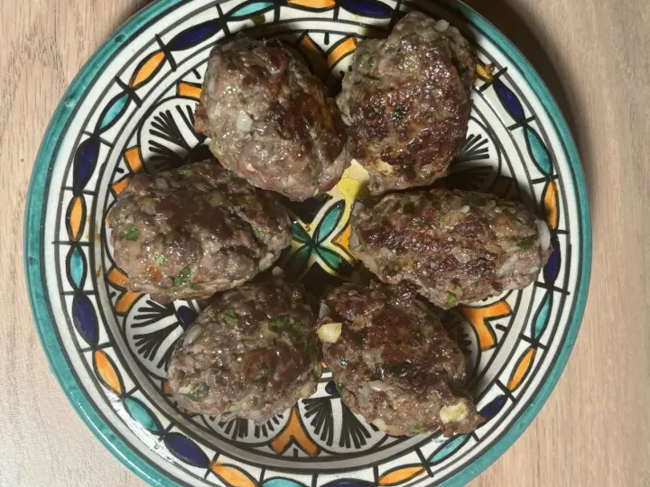 Cinq boulettes de kefta, prêtes à être dégustées, sur une assiette décorée. Une recette simple et savoureuse.