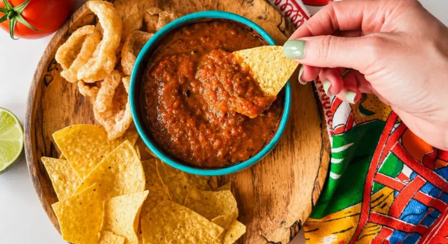 Une main trempe une chips dans une sauce salsa maison. Parfait pour une sauce salsa recette rapide et savoureuse.