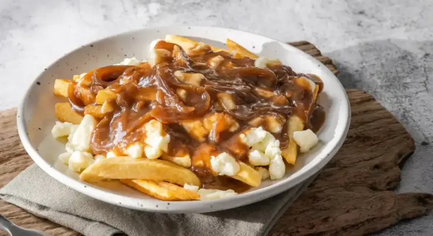 Une assiette de poutine fumante, parfaite pour une recette poutine maison facile. Des frites croustillantes, du fromage en grains et une sauce brune onctueuse.