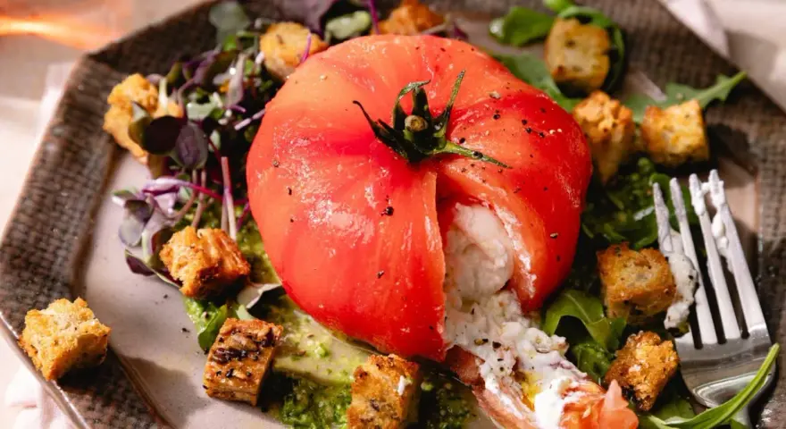 Une tomate farcie de burrata crémeuse, accompagnée de croûtons croustillants et d'une sauce verte. Une idée parfaite pour une recette burrata froide.