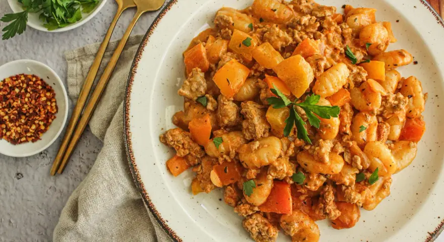 Délicieux sauté boeuf haché asiatique avec des gnocchis et des morceaux de carottes, garni de persil frais.
