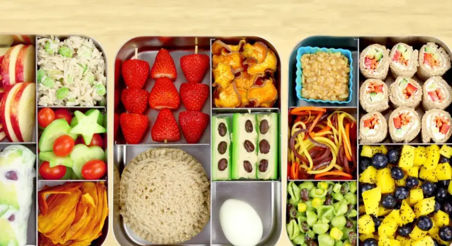 Une recette bento colorée et équilibrée : riz, fraises, crudités, sandwich, rouleaux de printemps, fruits et légumes variés.