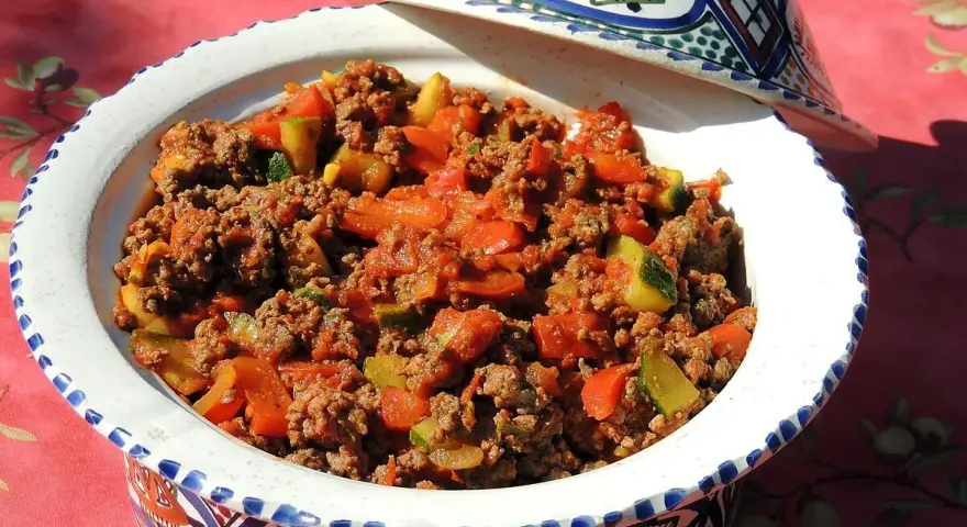 Un plat savoureux de recette viande hachée avec des légumes, servi dans un plat à tajine décoré.