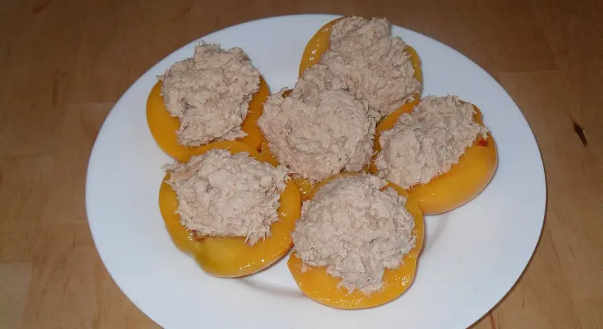 Moitié de pêches garnies d'une préparation de thon, prêtes pour un apéritif original. Une recette de pêche au thon revisitée.