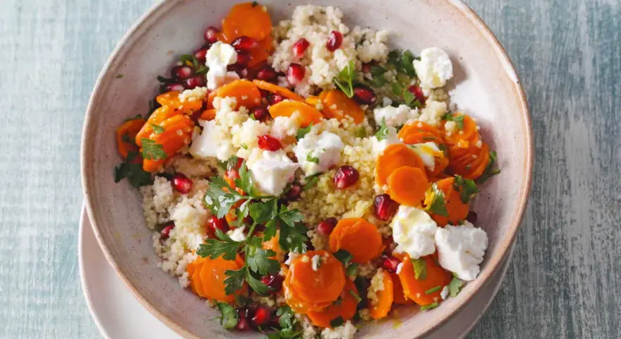 Salade de semoule colorée avec carottes, grenade et morceaux de feta. Un délice frais et savoureux.