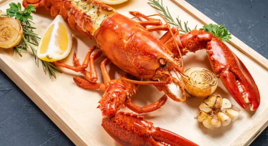 Homard entier, prêt pour la cuisson, garni de citron, d'oignons grillés et d'ail. Un délice pour les amateurs de fruits de mer.