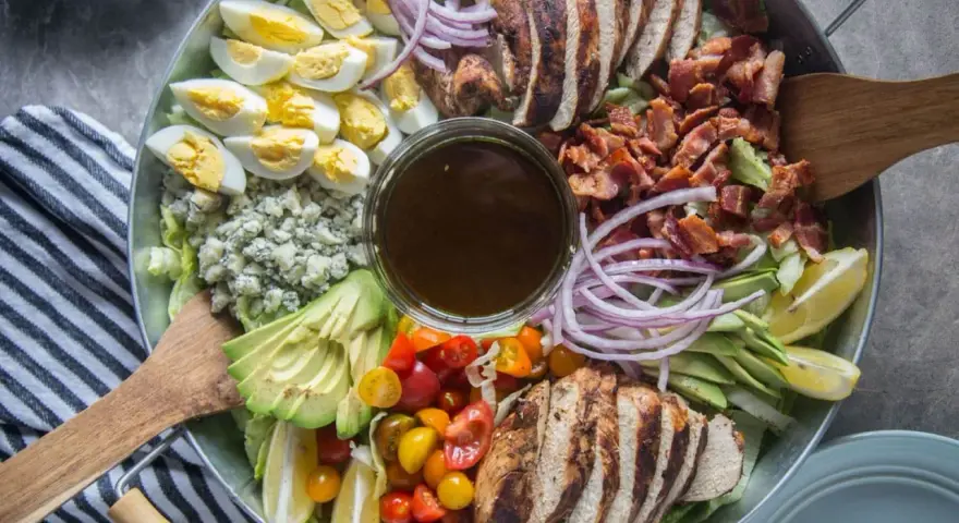 Salade généreuse avec poulet grillé, bacon croustillant, œufs durs, avocat, tomates cerises, oignons rouges et fromage bleu. Une salade kobe parfaite pour un repas complet.