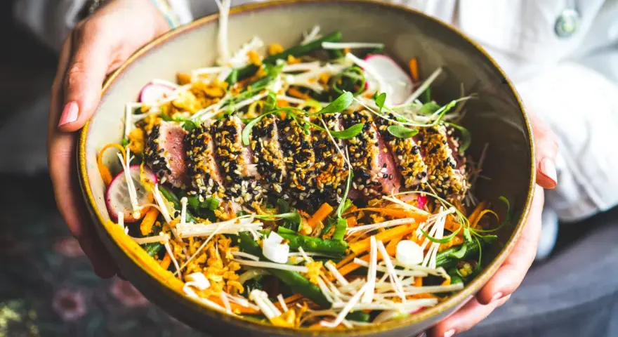 Un délicieux tataki de thon, enrobé de sésame, servi avec un accompagnement coloré de légumes croquants et de pousses fraîches.
