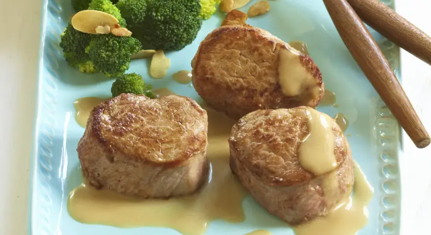 Trois médaillons de porc tendres nappés d'une onctueuse sauce moutarde, accompagnés de brocolis croquants. Un délice pour les amateurs de viande de porc.