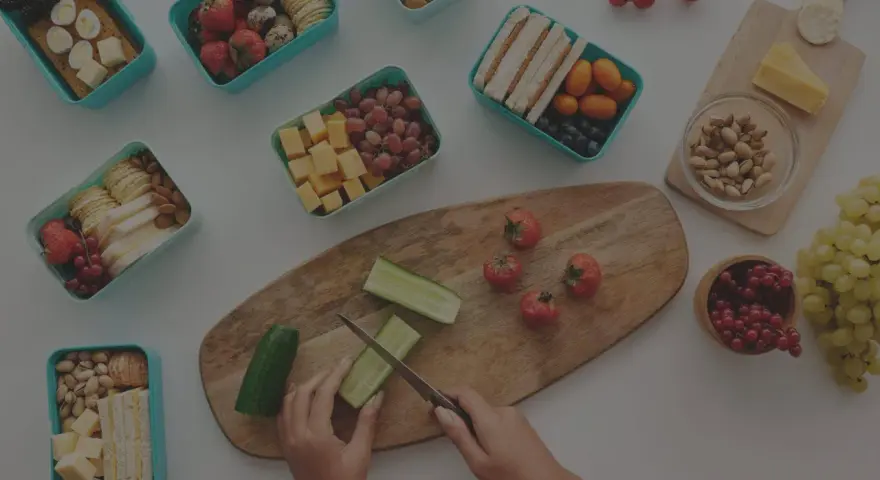 Préparation d'un panier repas travail de nuit : fruits, légumes, sandwichs, œufs, fromage et noix.