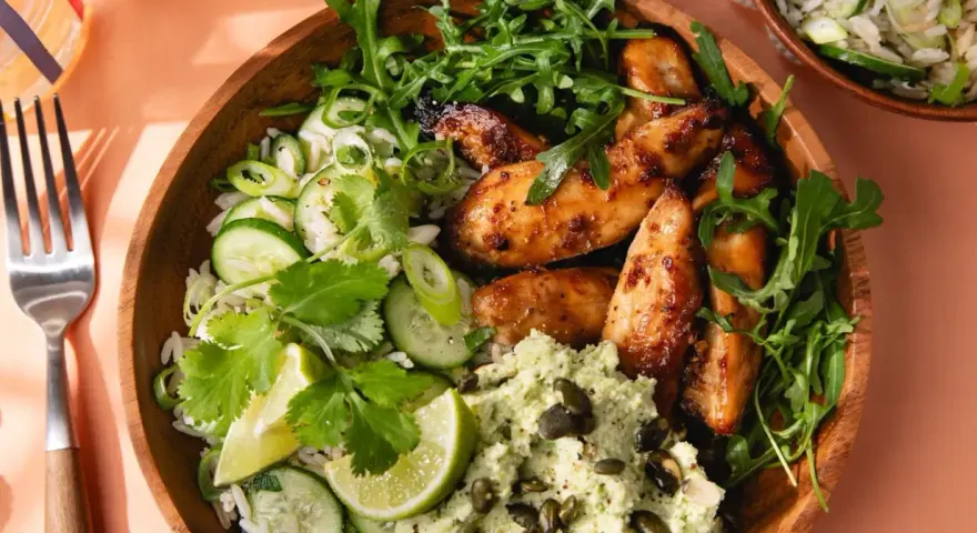 Un bol de riz avec poulet laqué, concombre, coriandre et une purée verte. Une délicieuse recette asiatique healthy.
