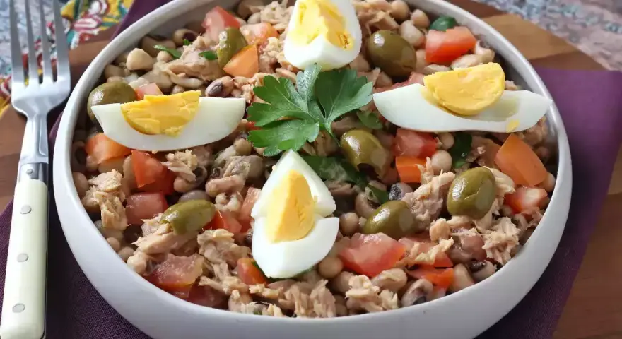 Salade de thon, haricots, tomates et olives, garnie d'œufs durs. Une idée repas facile et rapide.