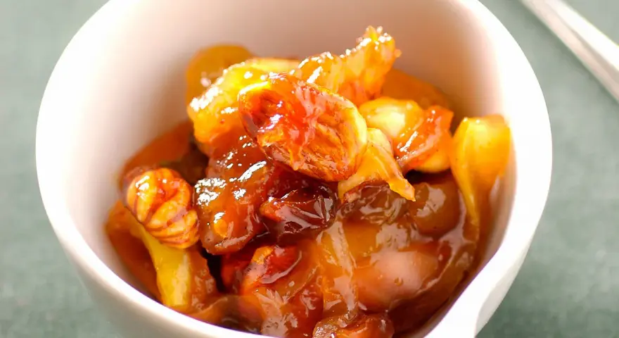 Chutney de prunes, un délice sucré-salé aux fruits confits et noix, servi dans un bol blanc.