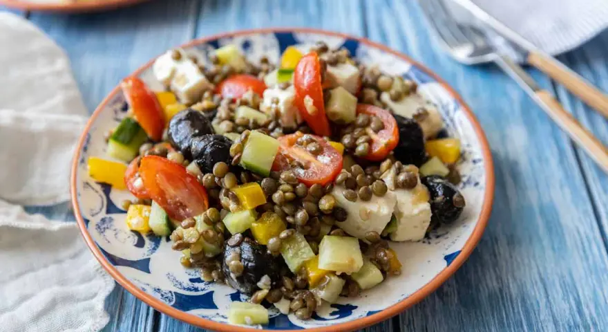 Salade de lentilles colorée avec tomates, concombre, poivrons, olives noires et feta. Un plat frais et savoureux.