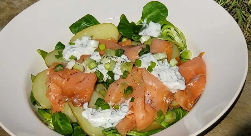Salade nordique appétissante : saumon fumé, pommes de terre, salade verte et sauce crémeuse aux herbes. Parfait pour un repas léger.