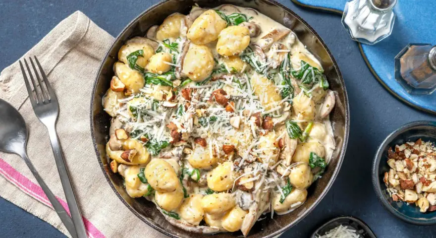Gnocchi crémeux aux champignons, épinards et noix, saupoudrés de parmesan. Un délice réconfortant.