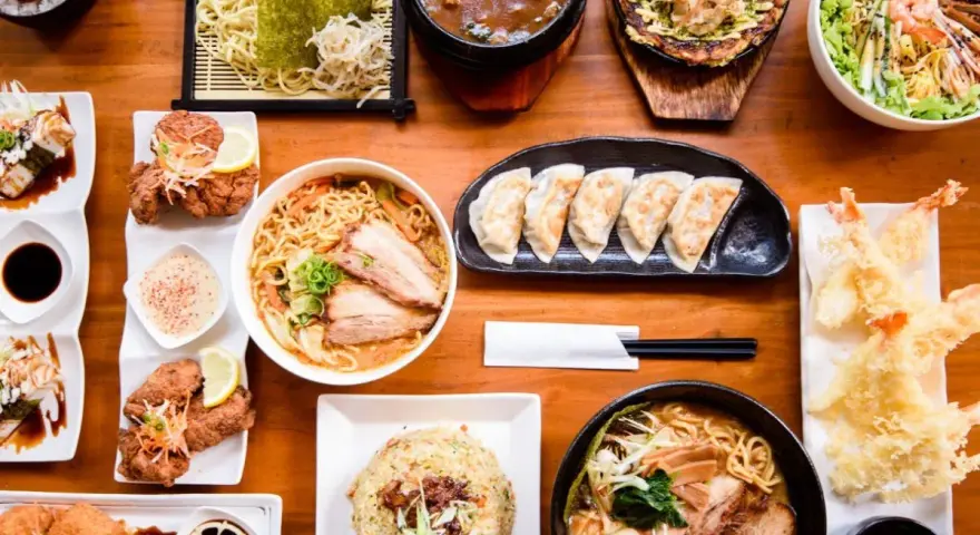Un festin de nourriture japonaise nom : ramen, tempura, gyoza, riz frit et plus encore, prêt à être dégusté.