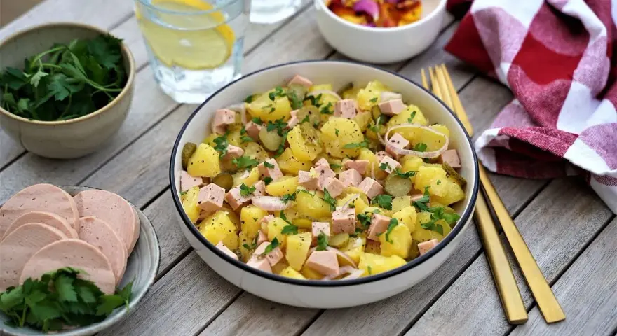 Salade strasbourgeoise appétissante avec pommes de terre, saucisse en dés, cornichons et persil frais. Un délice alsacien !