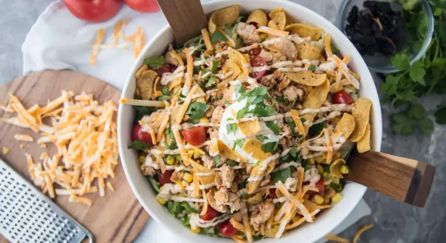Salade Tex Mex généreuse avec poulet émietté, maïs, tomates cerises, fromage râpé, éclats de tortilla et une touche de crème. Parfait pour un repas plein de saveurs.