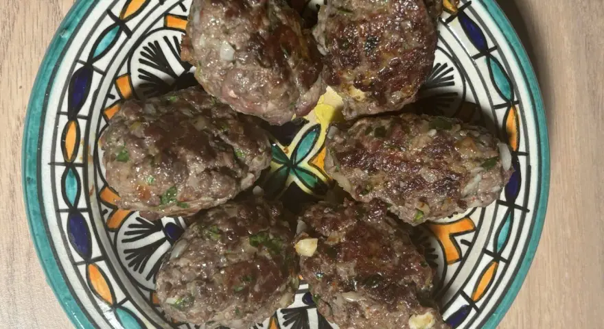 Cinq boulettes de kefta, prêtes à être dégustées, sur une assiette décorée. Une recette simple et savoureuse.