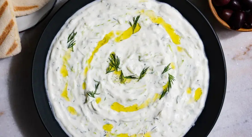 Un plat de tzatziki crémeux, garni d'aneth frais et d'huile d'olive. Parfait pour accompagner votre recette de tzatziki maison.