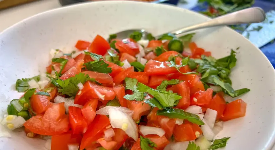 Un bol de pico de gallo frais, garni de coriandre, prêt à être dégusté.