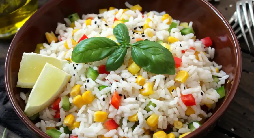 Salade niçoise riz colorée avec maïs, poivrons, basilic et quartiers de citron vert.