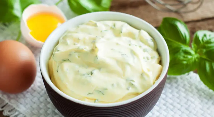 Mayonnaise onctueuse au basilic, avec un œuf et des feuilles de basilic frais.