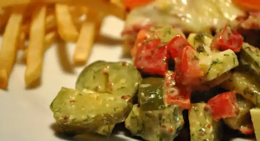 Une délicieuse salade de cornichon avec des tomates et des herbes, accompagnée de frites croustillantes.