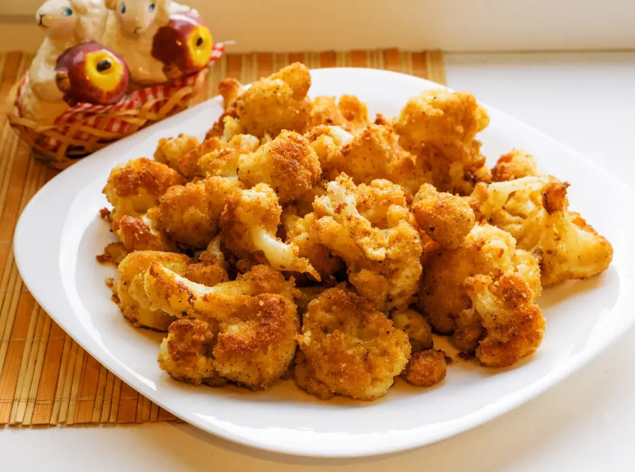 Choux fleur en tranche au four, dorés et croustillants, servis sur une assiette blanche. Un plat savoureux et sain.