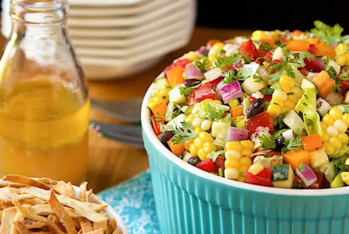 Salade mexicaine recette : ma&iuml;s, haricots noirs, tomates, poivrons, oignons rouges et coriandre fra&icirc;che dans un bol bleu.