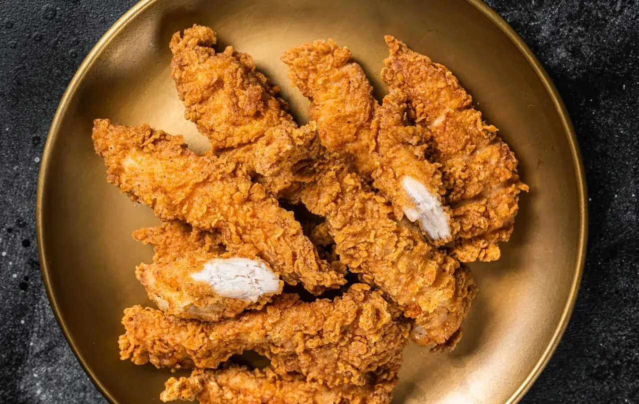 Un tas de poulet pan&eacute; croustillant et dor&eacute; sur une assiette dor&eacute;e.