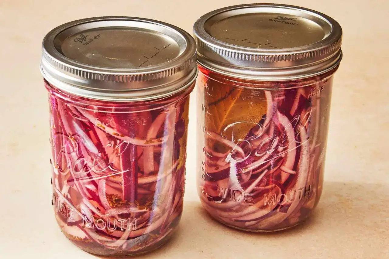 Deux bocaux remplis de pickles d'oignon rouge, prêts à ajouter une touche acidulée à vos plats.