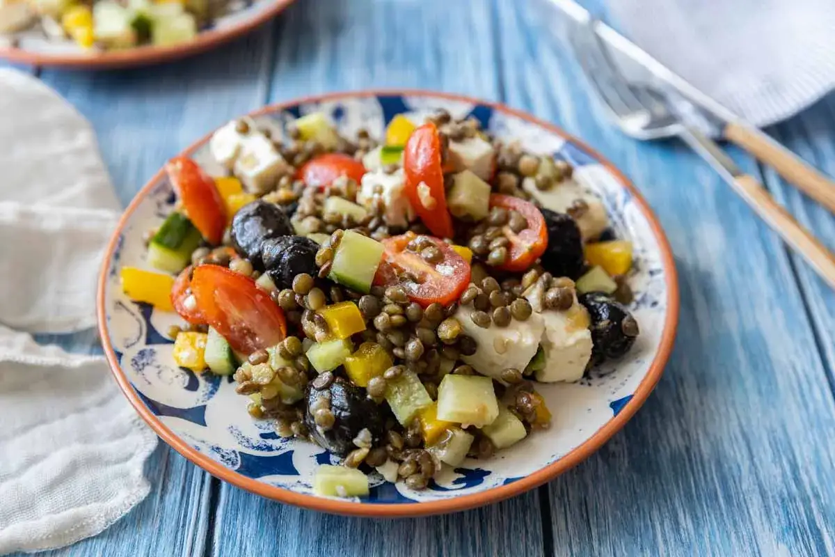 Une assiette color&eacute;e de salade de lentilles, garnie de tomates, concombre, olives noires et feta. Un d&eacute;lice frais et sain.