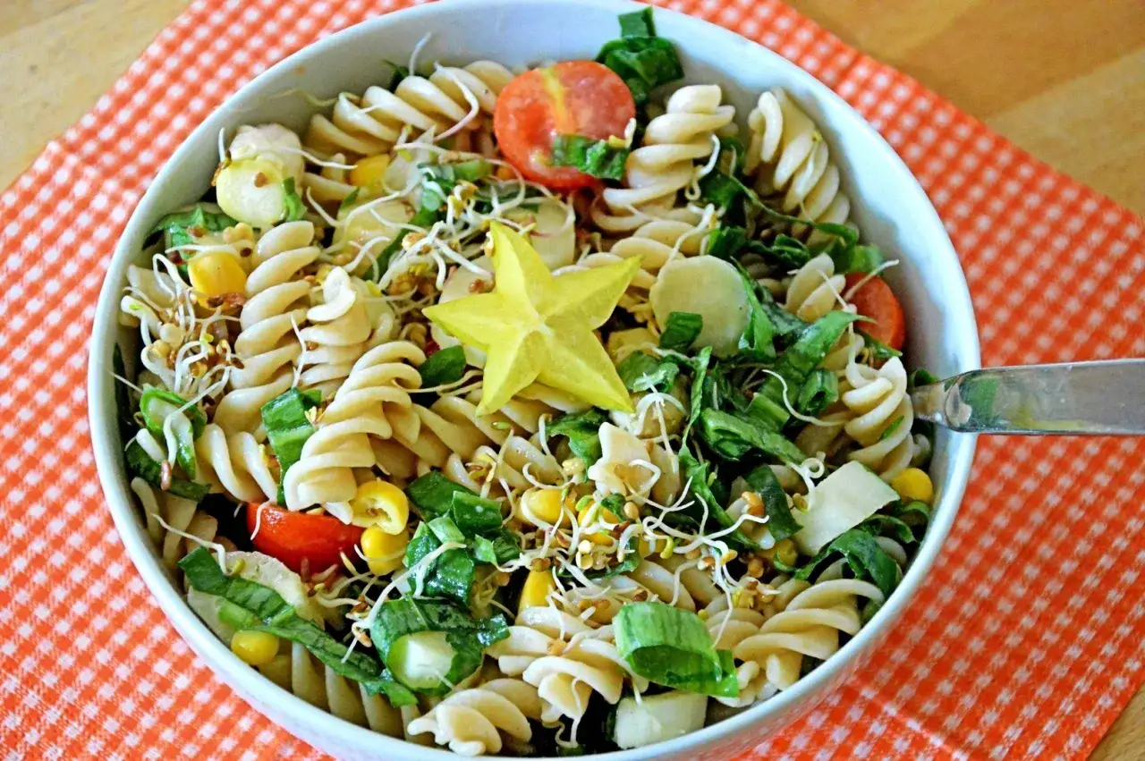 Salade de pâtes colorée avec étoile de carambole, maïs, tomates et pousses. Un repas facile à emporter en vacances, parfait pour un pique-nique.