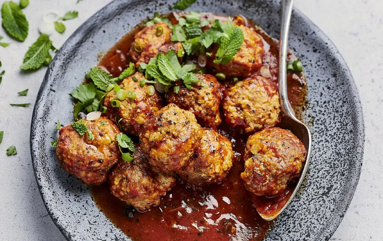 Boulettes de viande hachée savoureuses, nappées d'une sauce rouge et garnies de menthe fraîche. Une recette facile et délicieuse.