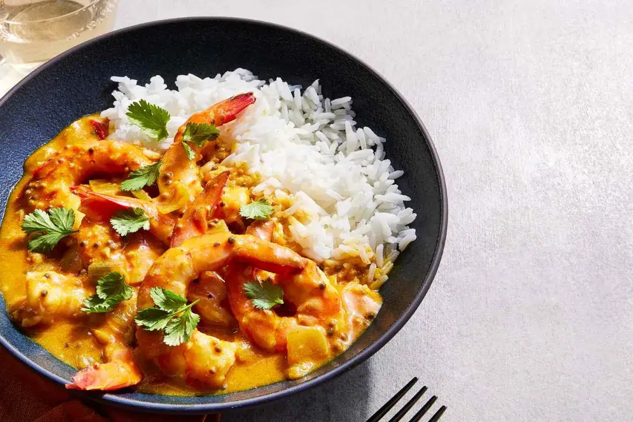 Un plat de crevette curry coco onctueux, servi avec du riz blanc et garni de coriandre fra&icirc;che. Un d&eacute;lice exotique.