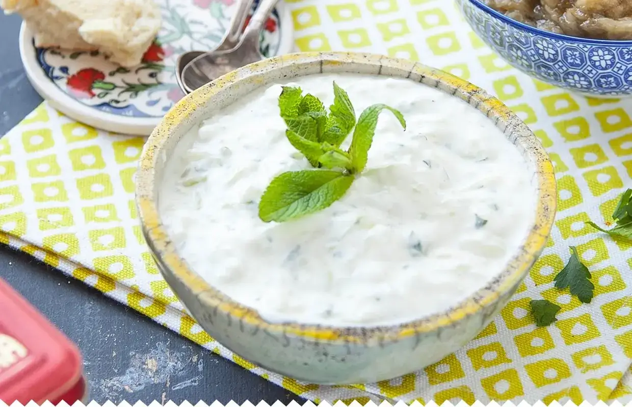 Un bol de tzatziki crémeux, garni de menthe fraîche. Parfait pour accompagner votre recette tzatziki maison.