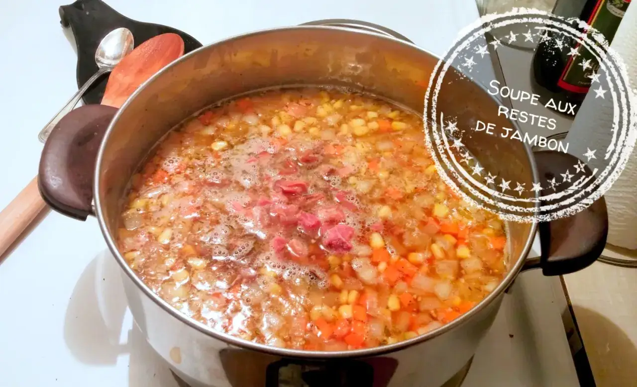 Une délicieuse soupe aux restes de jambon, avec des carottes et du maïs, mijote dans une marmite. Parfait pour savoir que faire avec des restes de jambon.