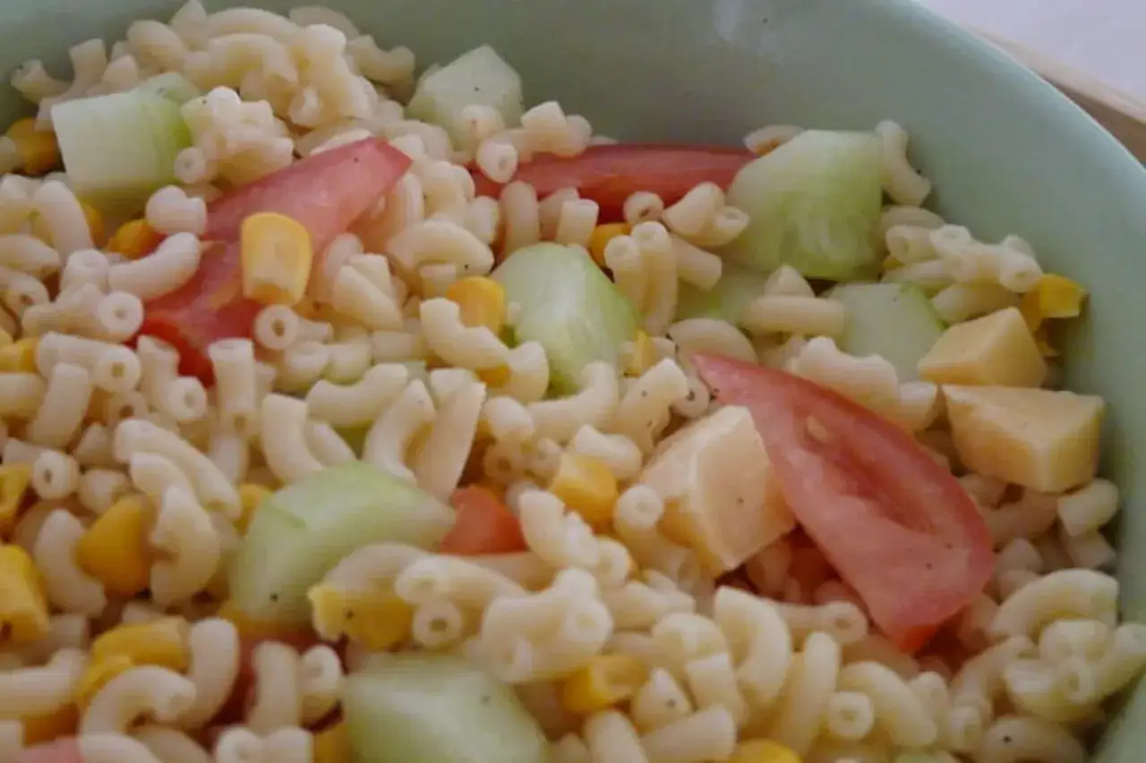 Salade de p&acirc;tes color&eacute;e avec des morceaux de tomates, de concombre, de ma&iuml;s et de fromage. Un plat estival parfait.
