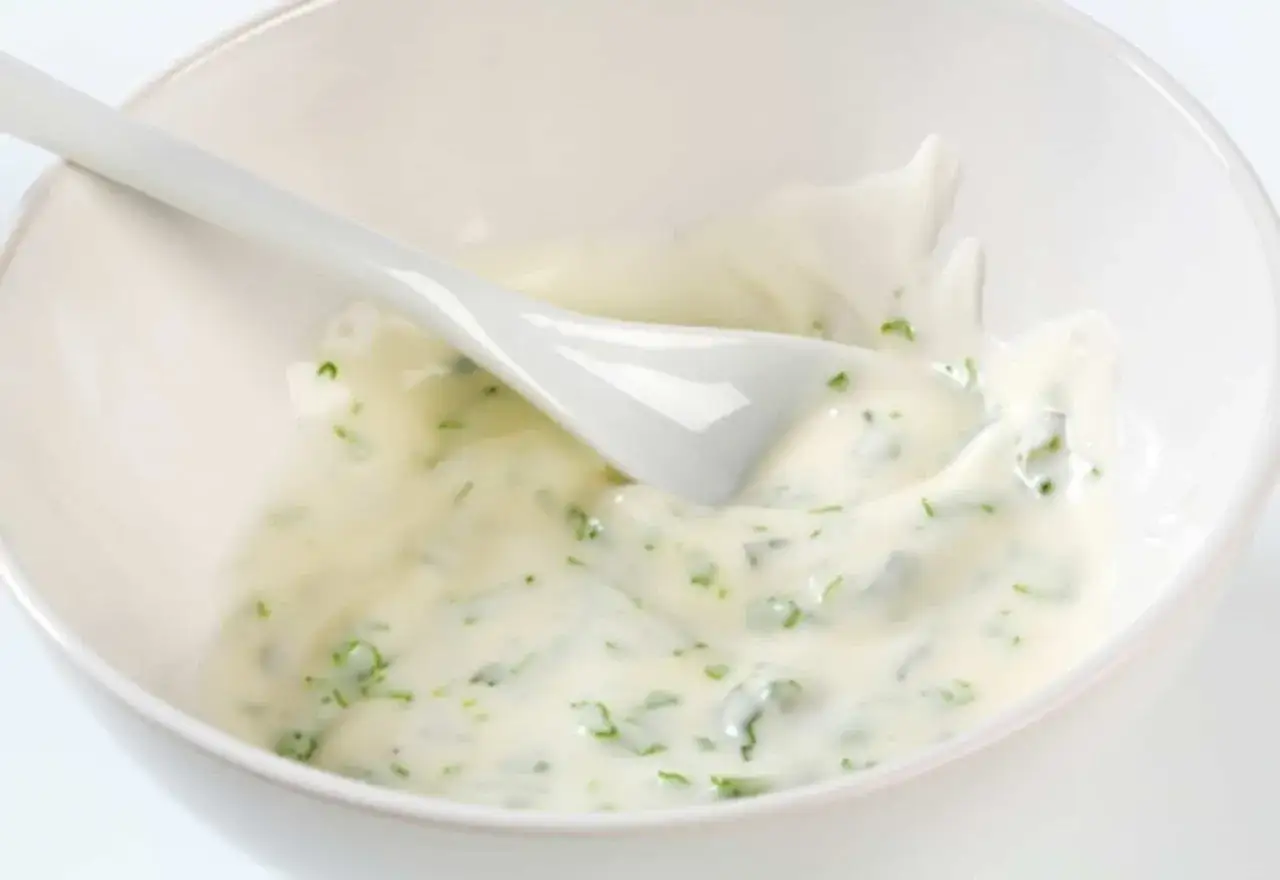 Mayonnaise onctueuse au basilic frais, servie dans un bol blanc avec une cuill&egrave;re.