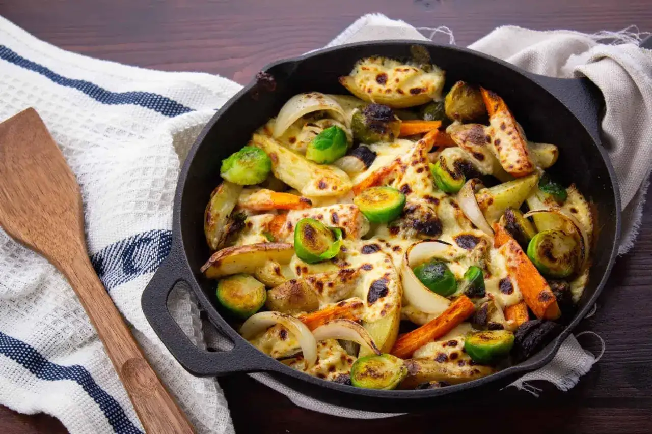Plat de l&eacute;gumes r&ocirc;tis au fromage dans une po&ecirc;le en fonte, parfait pour un d&icirc;ner rapide et facile. Pommes de terre, carottes, oignons et choux de Bruxelles fondants.