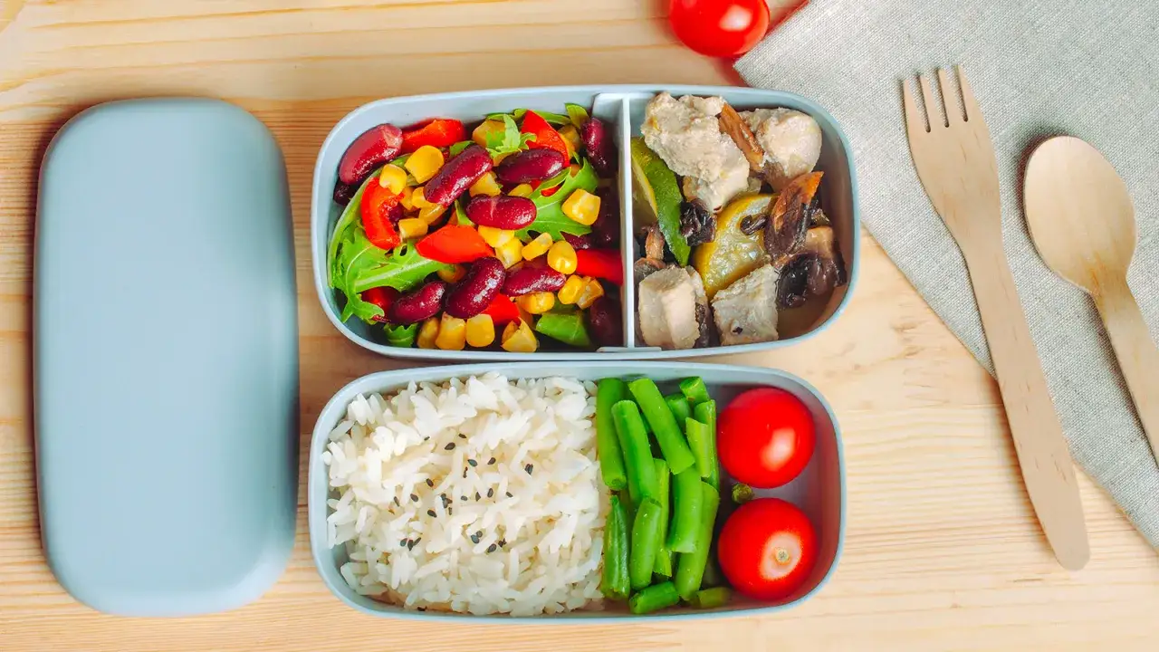 Un bento box avec un d&eacute;jeuner vegan : salade color&eacute;e, riz, haricots verts et tomates. Parfait pour un repas sain et &eacute;quilibr&eacute;.