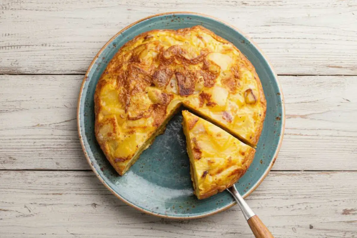 Tortilla espagnole, une recette simple et d&eacute;licieuse &agrave; base de pommes de terre et d'&oelig;ufs, servie sur une assiette bleue.