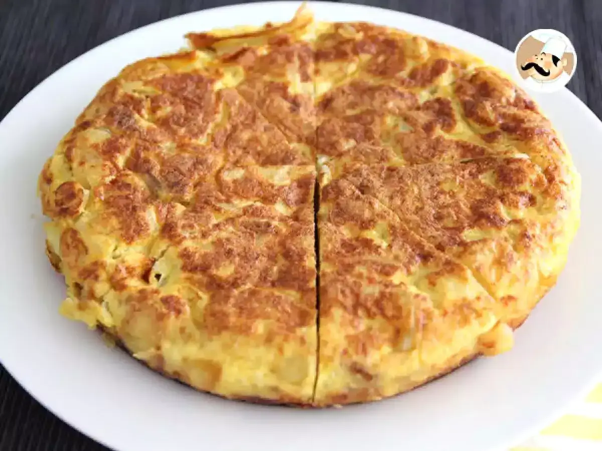 Une tortilla espagnole dor&eacute;e et app&eacute;tissante, coup&eacute;e en quartiers sur une assiette blanche.