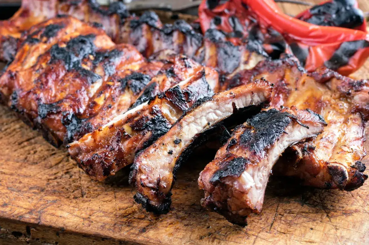 D&eacute;licieux ribs au four, caram&eacute;lis&eacute;s et l&eacute;g&egrave;rement grill&eacute;s, pr&eacute;sent&eacute;s sur une planche en bois. Un d&eacute;lice &agrave; savourer !