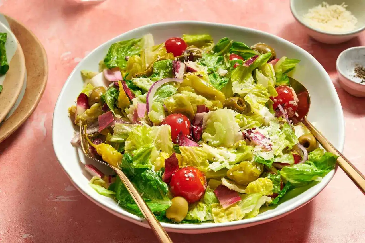 Une généreuse salade italienne croquante avec laitue, tomates cerises, olives, oignons rouges et fromage râpé.